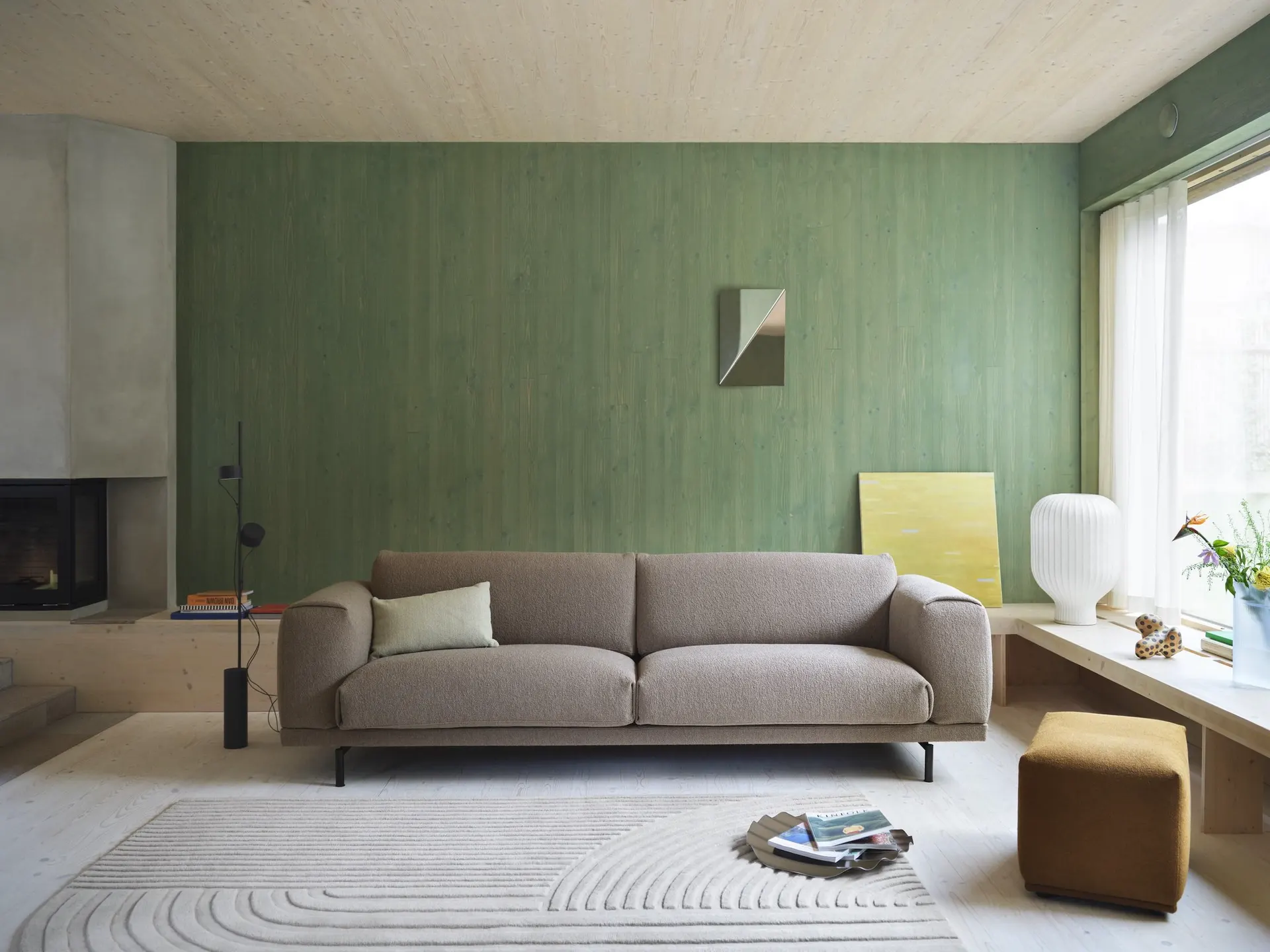 Modernes Wohnzimmer mit grauem Muuto-Sofa vor grüner Wand