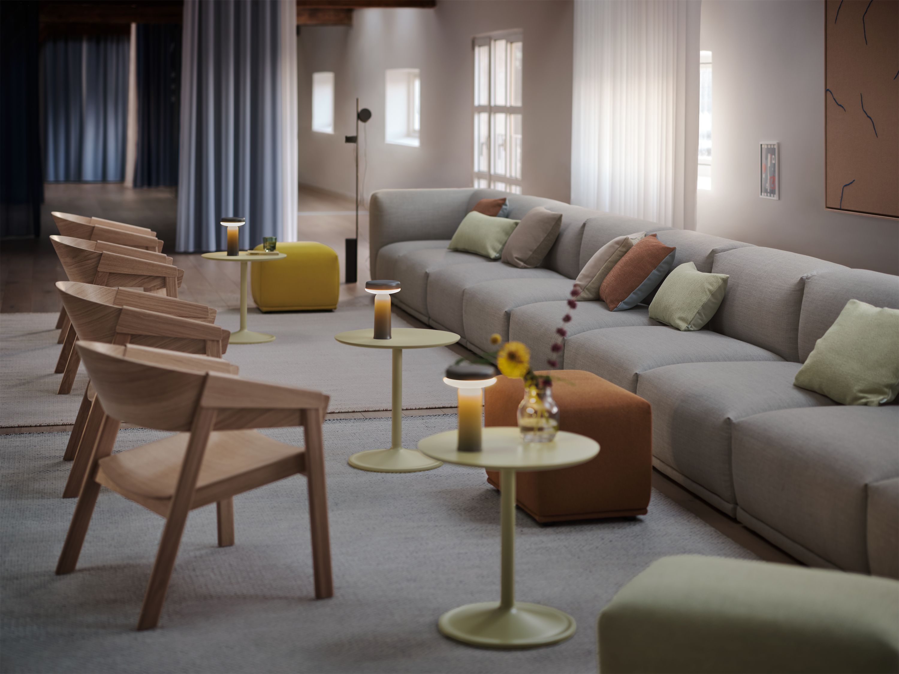 Große Lounge mit grauem Modulsofa, einer Reihe Eichensessel und gelbem Sitzhocker.