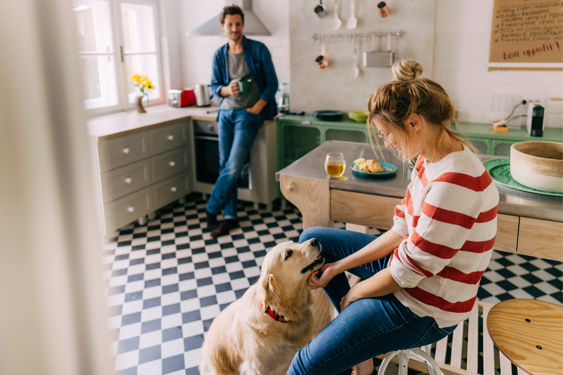 Junges Paar entspannt beim Frühstück mit Hund in einer gemütlichen Küche - Inspiration für das unkomplizierte Lebensgefühl von Nuance Living.