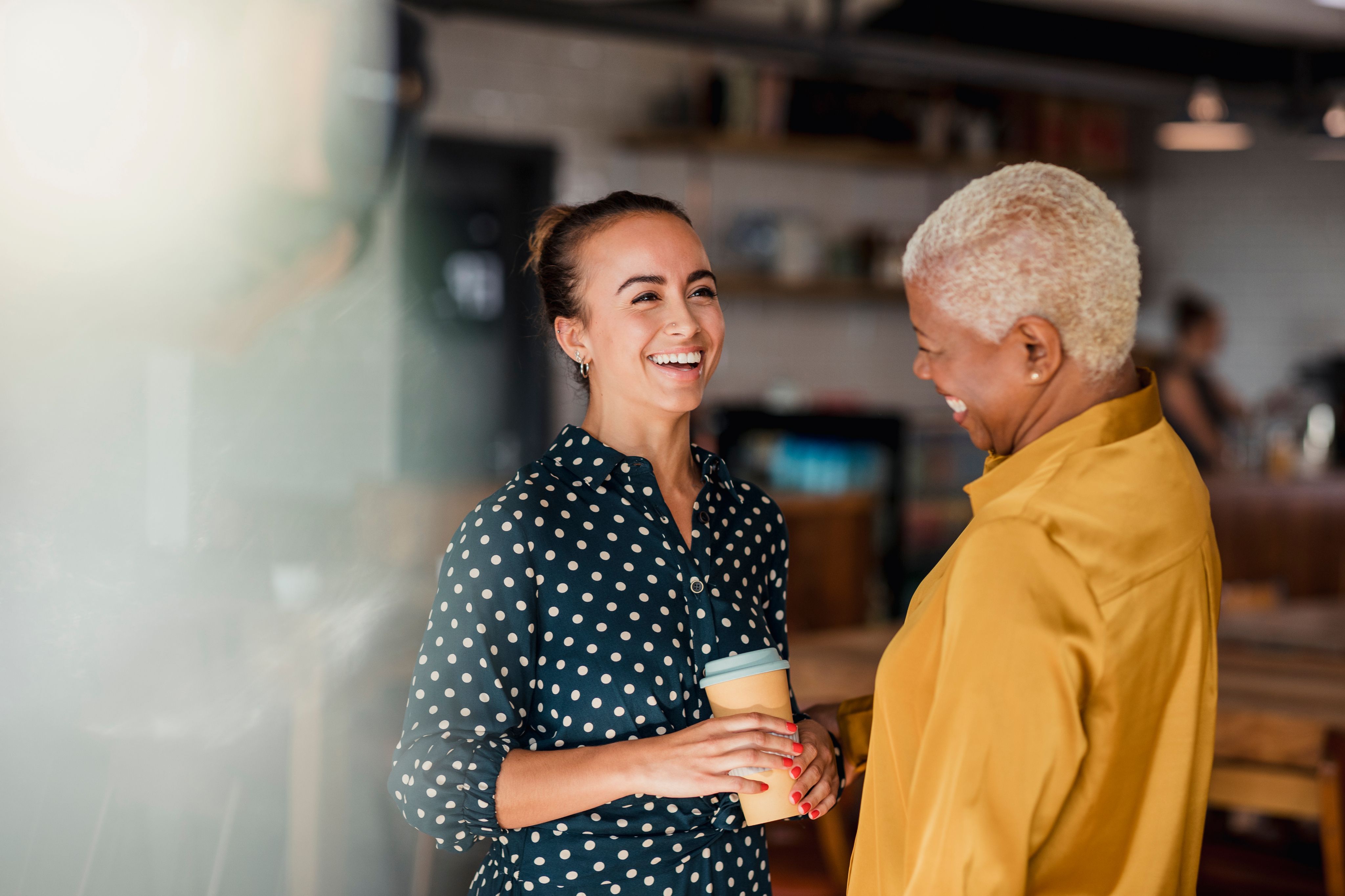 Junge und ältere Frau lachen entspannt bei einem Kaffee – Symbolbild für eine persönliche Beratung und den Start in einen neuen Lebensabschnitt mit Nuance Living.