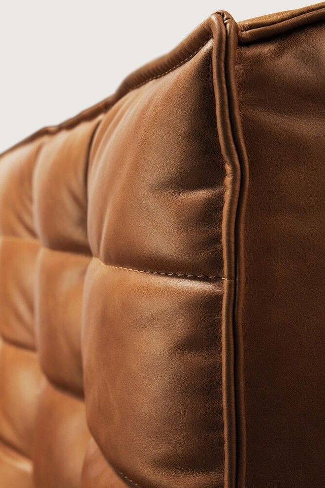 Detailaufnahme eines cognacfarbenen Ledersofas, die die hochwertige Steppung und die natürliche Textur des Materials zeigt