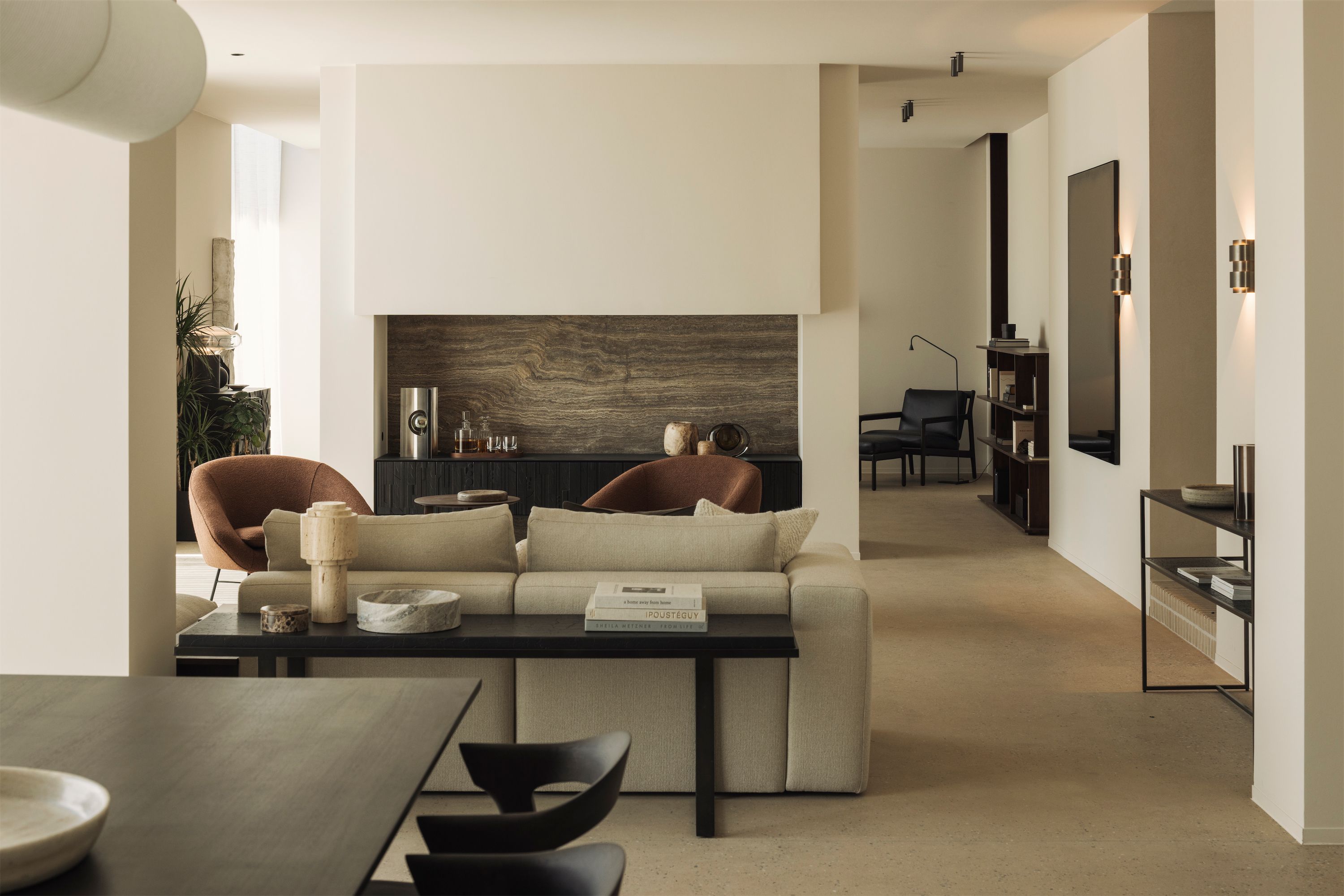 Wohnzimmer mit beigem Sofa, terracottafarbenen Bouclé-Sesseln und Steinkamin – Home Staging.