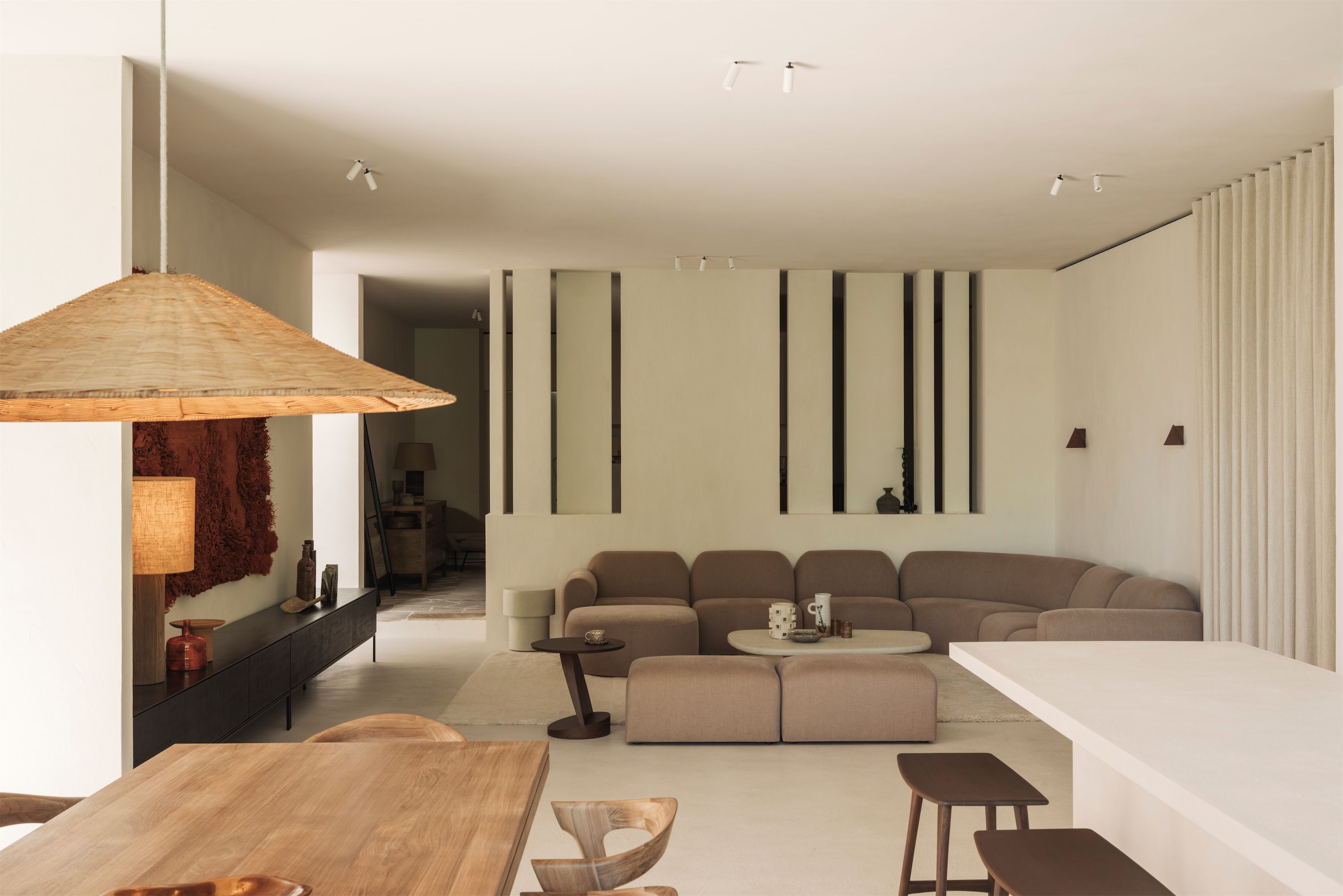 Wohnzimmer mit grauem Designsofa, Bogenstehleuchte und Teppich in warmen Erdtönen.